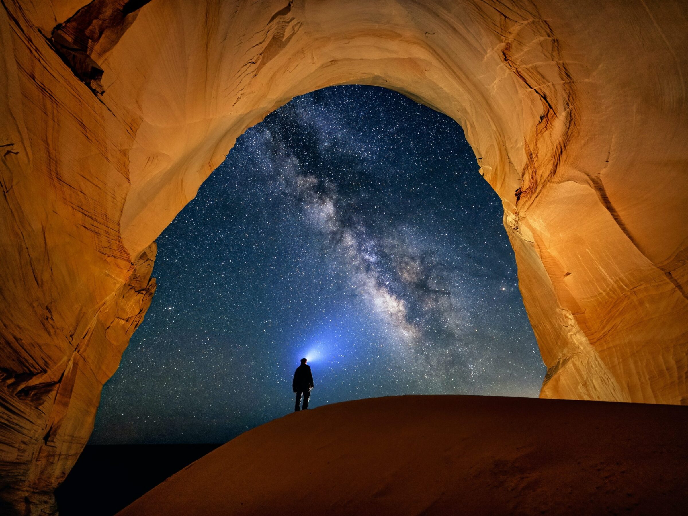 An image of a person looking out of a cave into the night sky