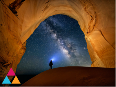 A person in a large cave looking out into the night sky