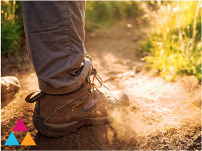 A leg dressed for hiking on a path outdoors on a sunny day